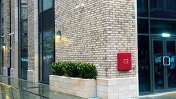 A secured premises information box mounted near a building entrance for firefighter access.